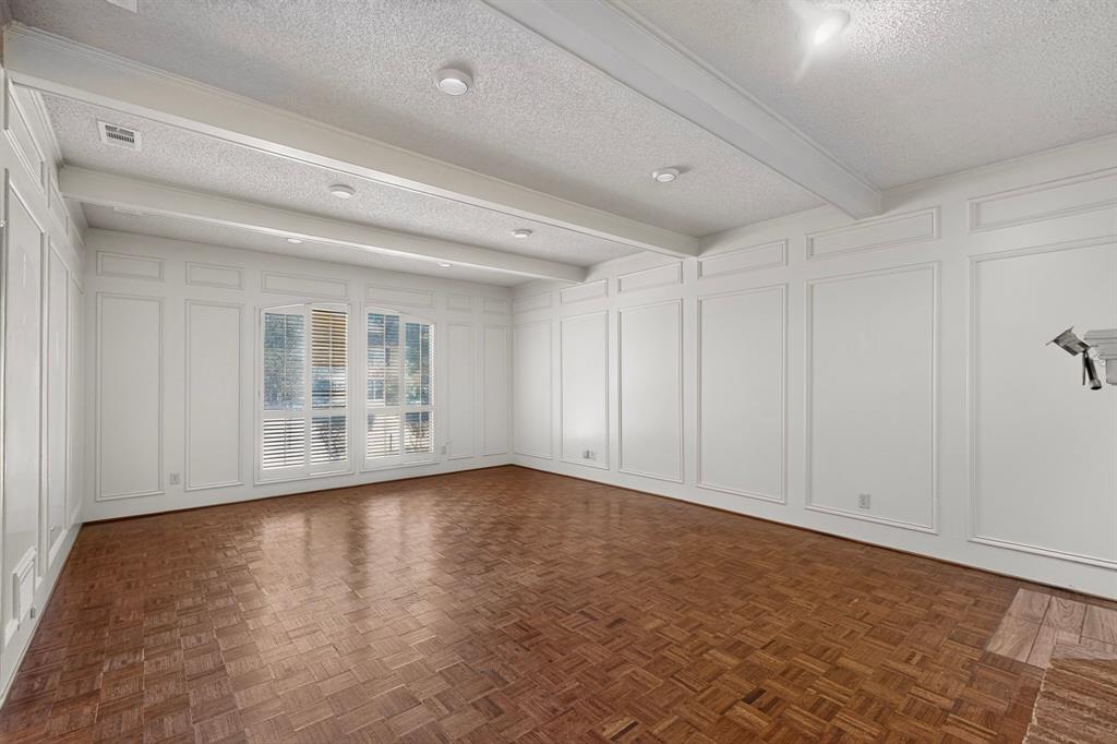 Parquet wood-finish flooring, recessed lighting, decorative wall paneling, and a beamed ceiling