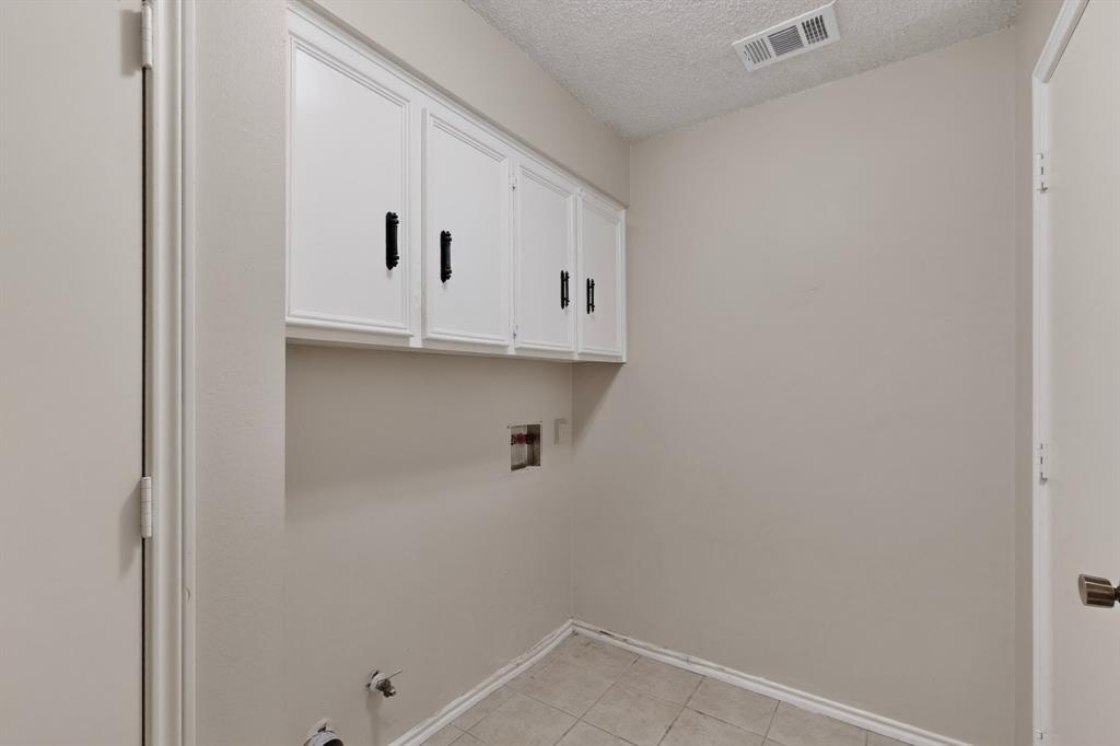 White cabinetry with black hardware, tile flooring, and light neutral wall paint