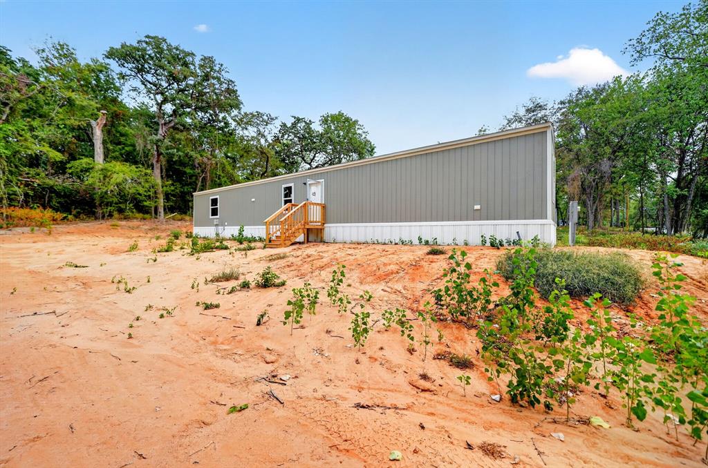 Single-level exterior featuring vertical siding, a shed-style roofline, and wood-framed stairs