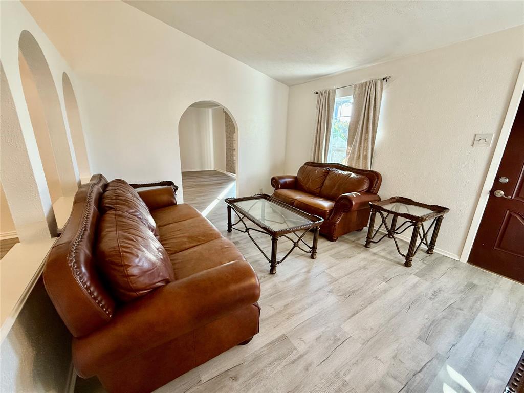 Light wood-finish flooring throughout, arched wall cutouts, and a window with curtain rods Light wood-finish flooring throughout, arched wall cutouts, and a window with curtain rods