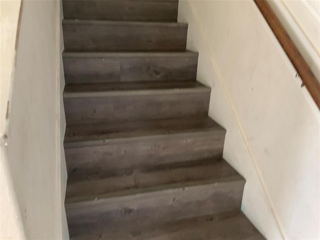 Staircase featuring wood-finish treads and risers, and a wood handrail