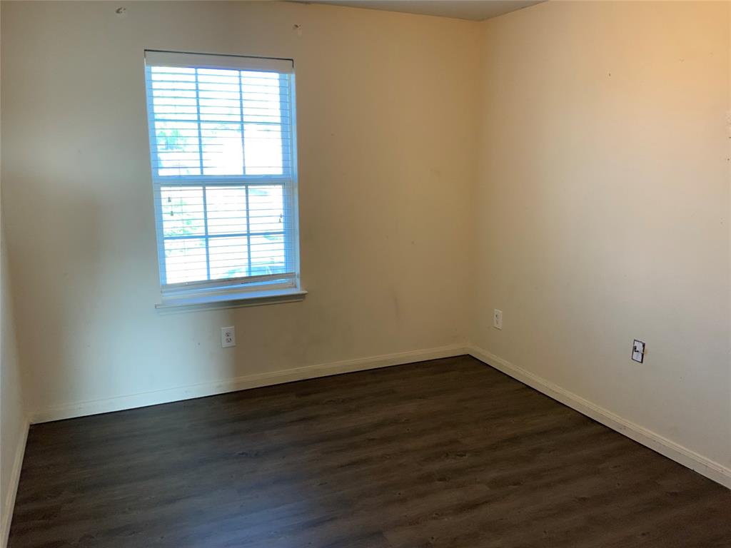 Wood-finish flooring with a window featuring horizontal blinds