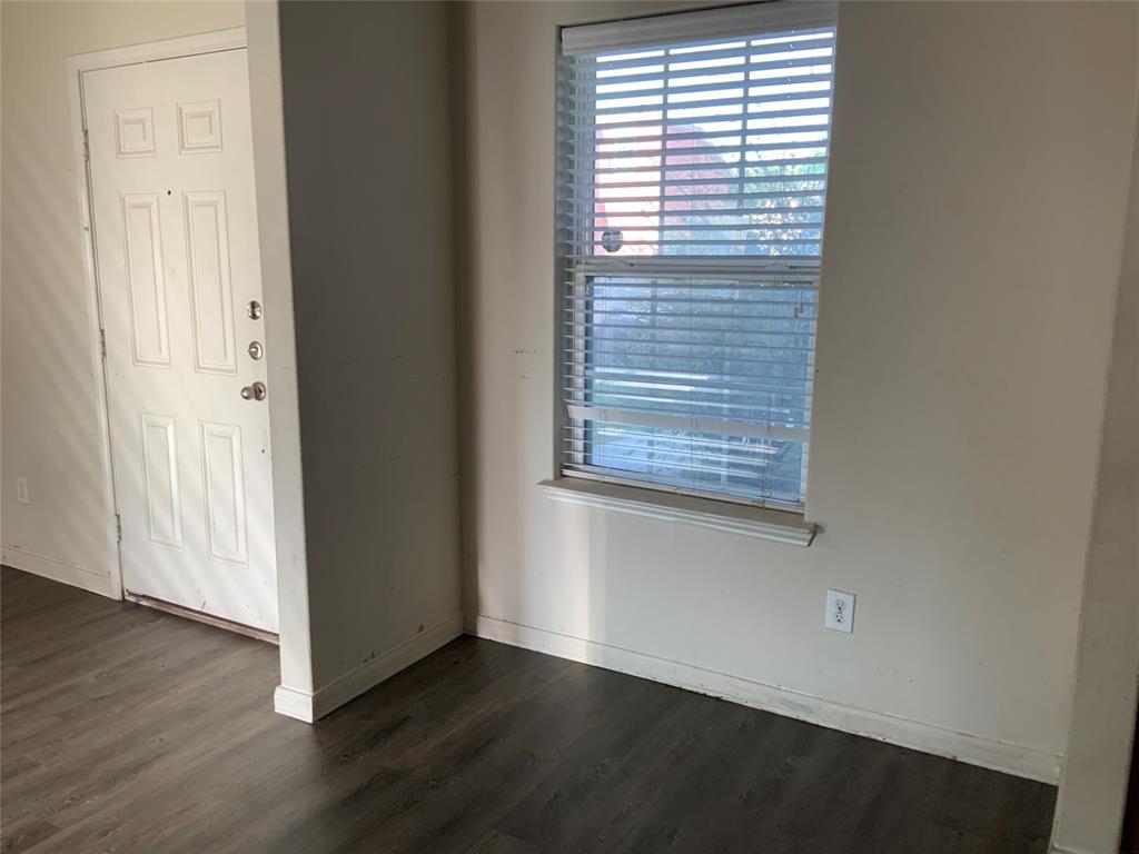 Wood-finish flooring with a white entry door featuring panel detailing Wood-finish flooring with a white entry door featuring panel detailing
