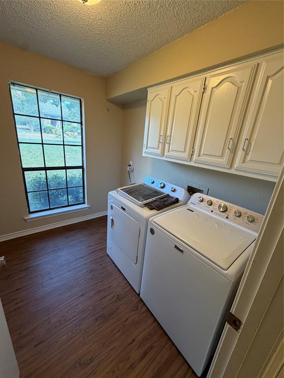 Wood-finish flooring, overhead cabinetry, and a window with exterior views