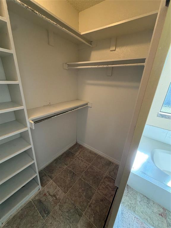 Built-in shelving, multiple hanging rods, and a tiled floor