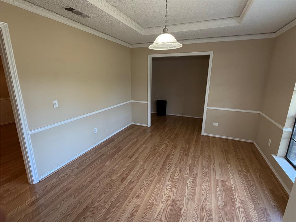 Wood-finish flooring, two-tone wall treatment with chair rail, recessed ceiling detail, and a white dome pendant light fixture
