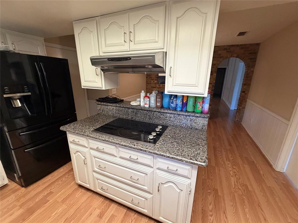 Kitchen island with built-in electric cooktop, white cabinetry, and a granite-finish countertop
