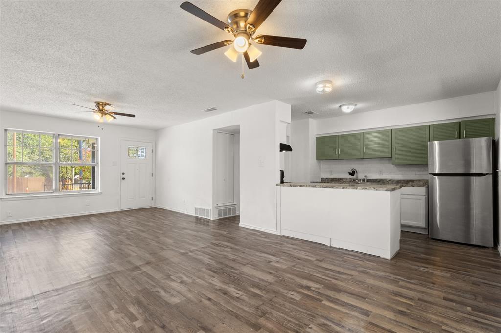 Open-concept living space featuring wood-finish flooring, white walls, and dual ceiling fans