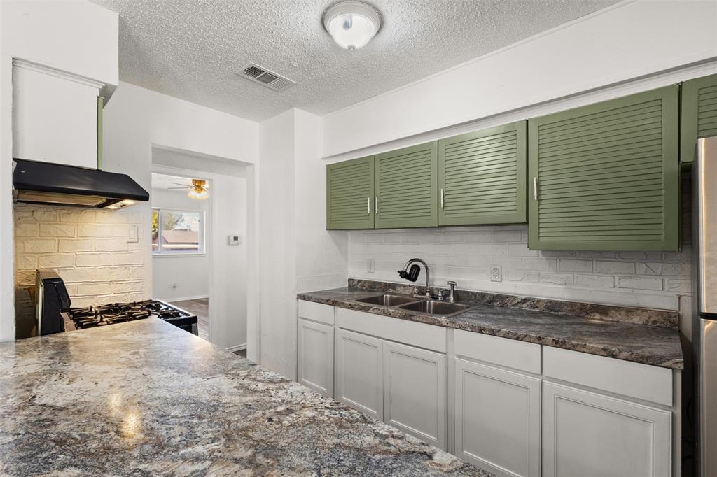 Kitchen featuring light green upper cabinetry, white lower cabinetry, and a double basin stainless steel sink