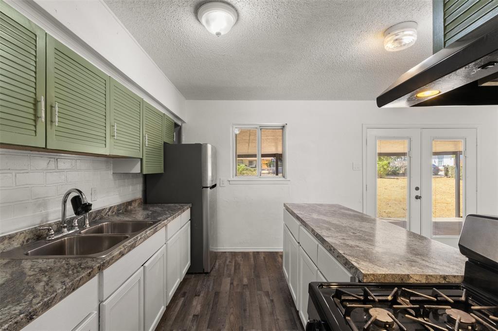 Kitchen featuring a dual basin sink, white cabinetry, wood-finish flooring, a center island with a countertop, and double glass doors leading to the exterior