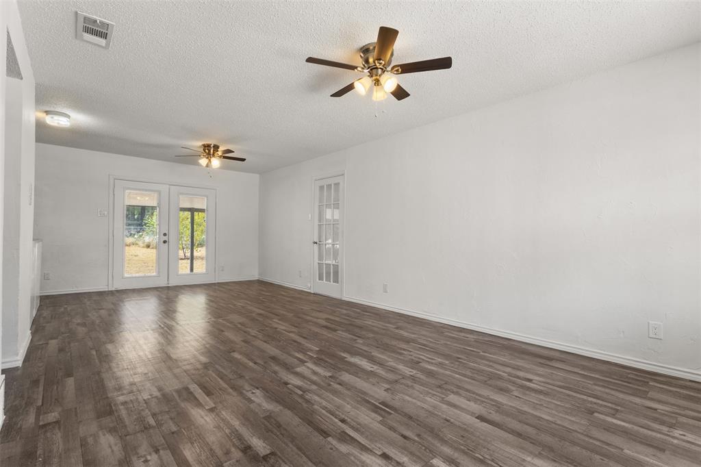 Spacious interior featuring wood-finish flooring, white walls, and dual ceiling fans