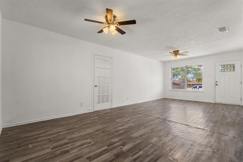 Wood-finish flooring, white painted walls, ceiling fans with integrated lighting, and a white paneled door with glass inserts