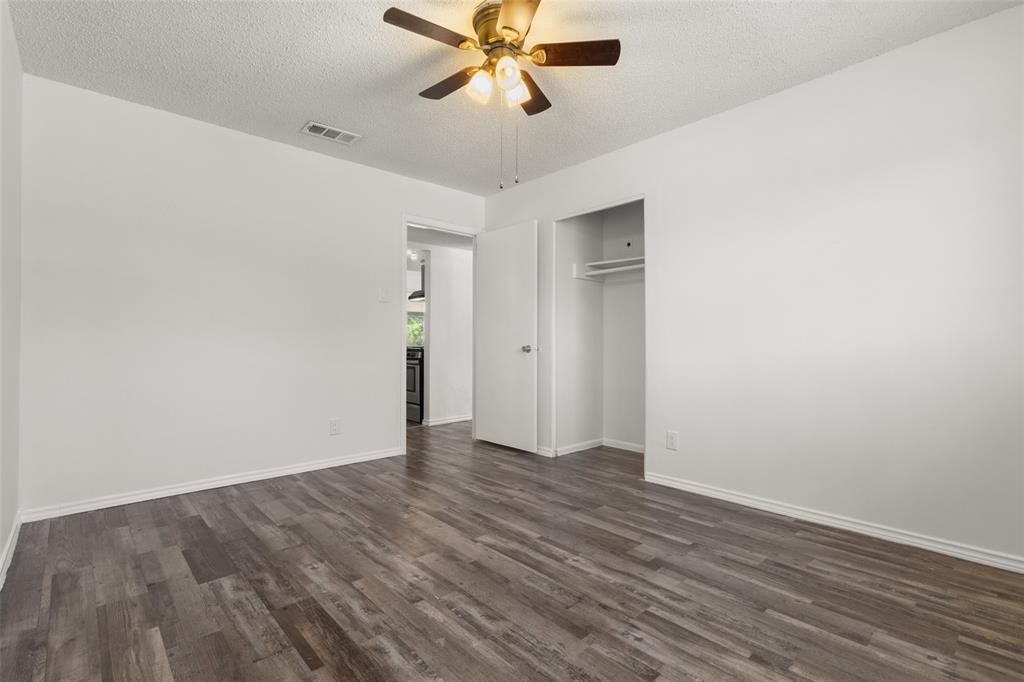 Wood-finish flooring, ceiling fan with integrated lighting, recessed clothing rod, and white walls