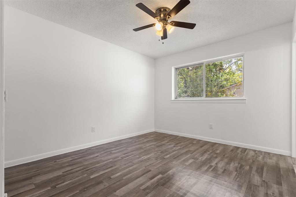 Wood-finish flooring, white walls, window, and ceiling fan with integrated lighting
