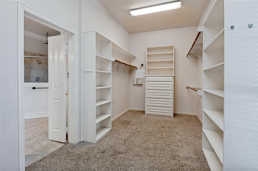 Walk-in closet featuring carpet flooring, built-in shelving, hanging rods, and a dresser with integrated shelving