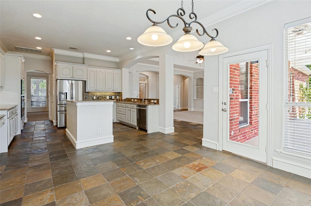 Spacious kitchen featuring stone flooring, white cabinetry, a kitchen island, stainless steel appliances, and a glass-paneled exterior door