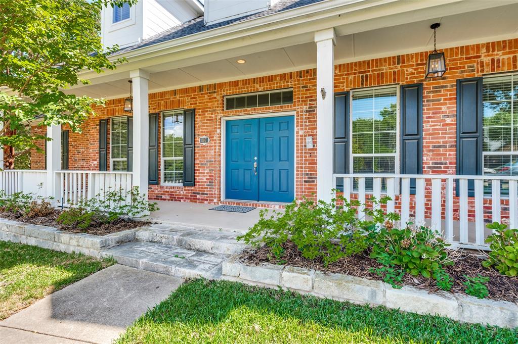 Brick exterior with a covered porch, white railing, and a vibrant blue double entry door