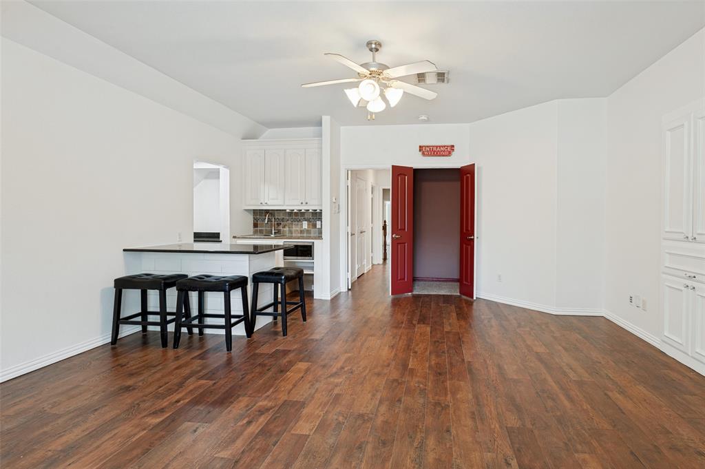 Wood-finish flooring, white cabinetry, island with countertop, ceiling fan, and built-in storage