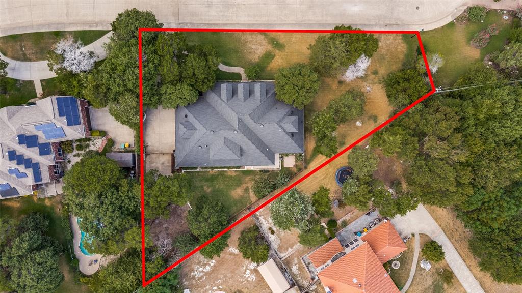 Property with mature tree coverage, a multi-gabled roofline, and a paved driveway
