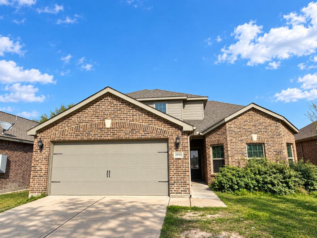 Brick exterior with an attached garage, paved driveway, and established front landscaping Brick exterior with an attached garage, paved driveway, and established front landscaping