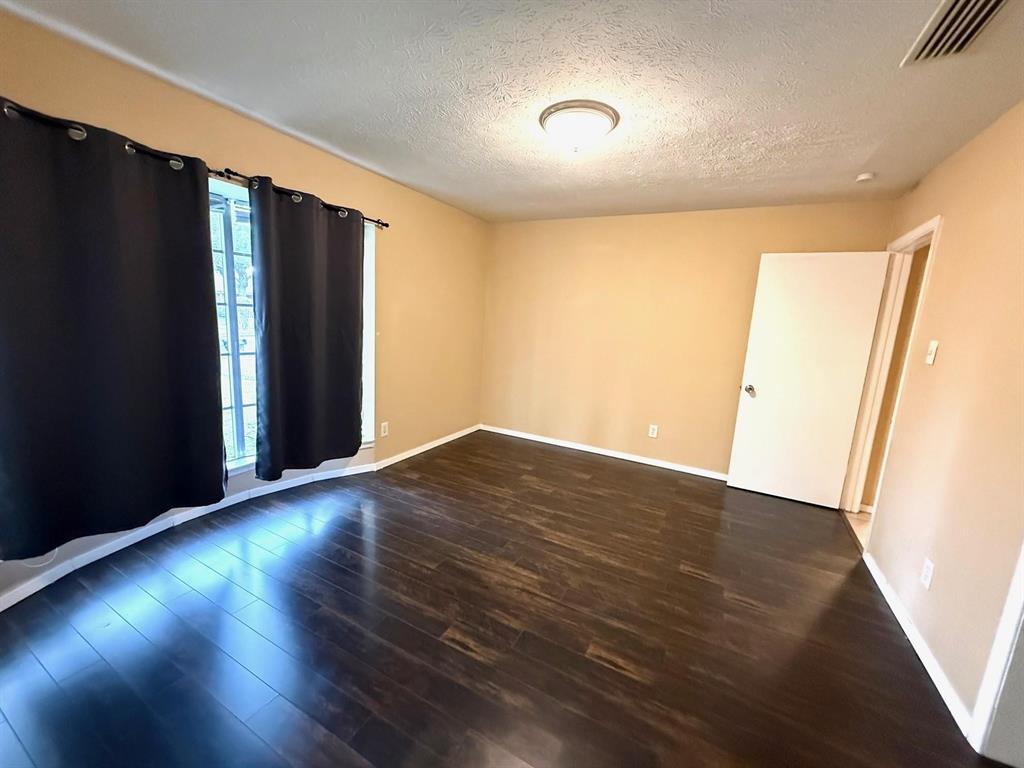 Wood-finish flooring with a smooth finish, neutral wall tones, and recessed lighting