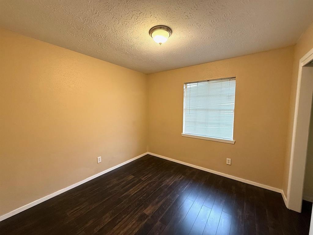 Wood-finish flooring, single window with blinds, ceiling-mounted light fixture