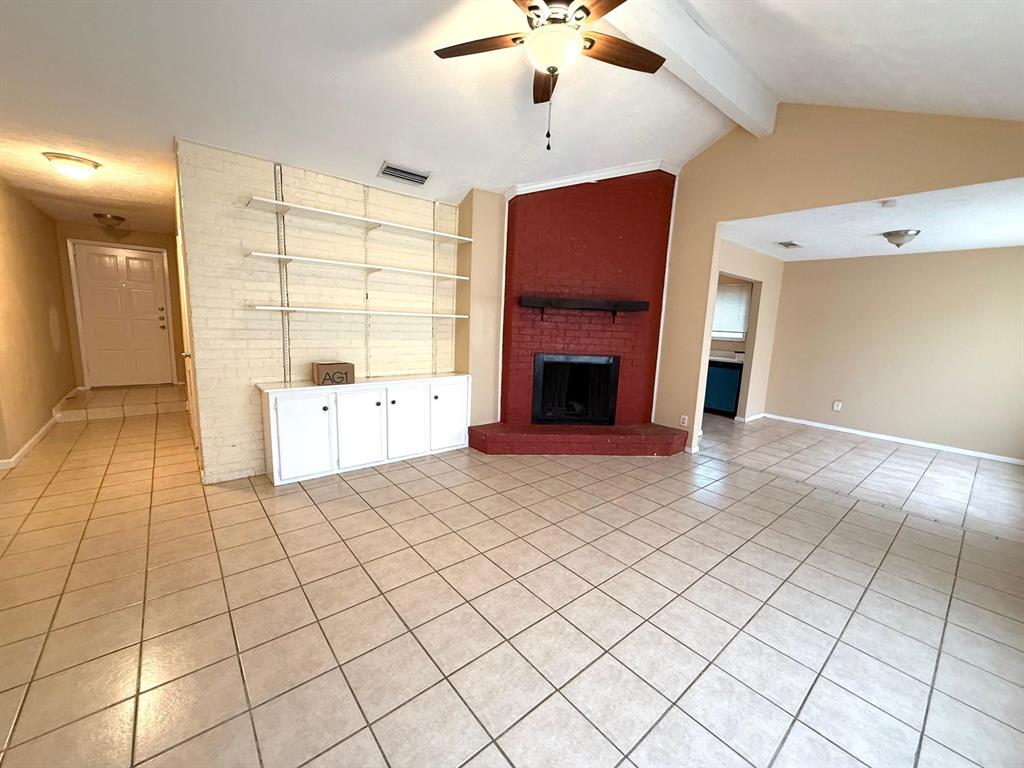 Vaulted ceiling with exposed beams, ceiling fan, and tiled flooring