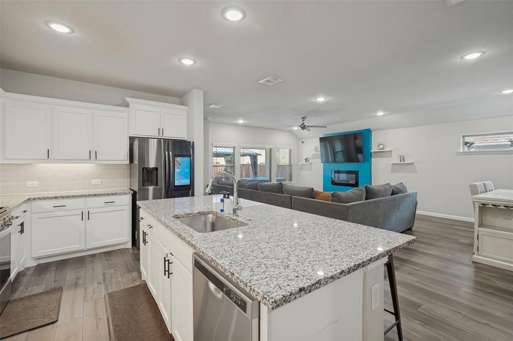White cabinetry, stainless steel appliances, granite countertops, wood-finish flooring, and recessed lighting
