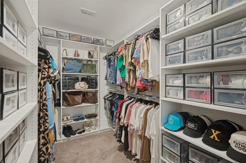 Walk-in closet featuring extensive built-in shelving, multiple hanging rods, and recessed lighting