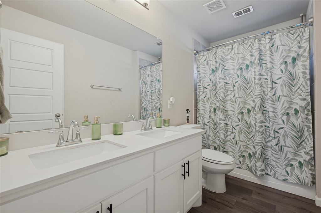Dual vanity with integrated sinks, chrome fixtures, white cabinetry with black hardware, and a shower-tub combination