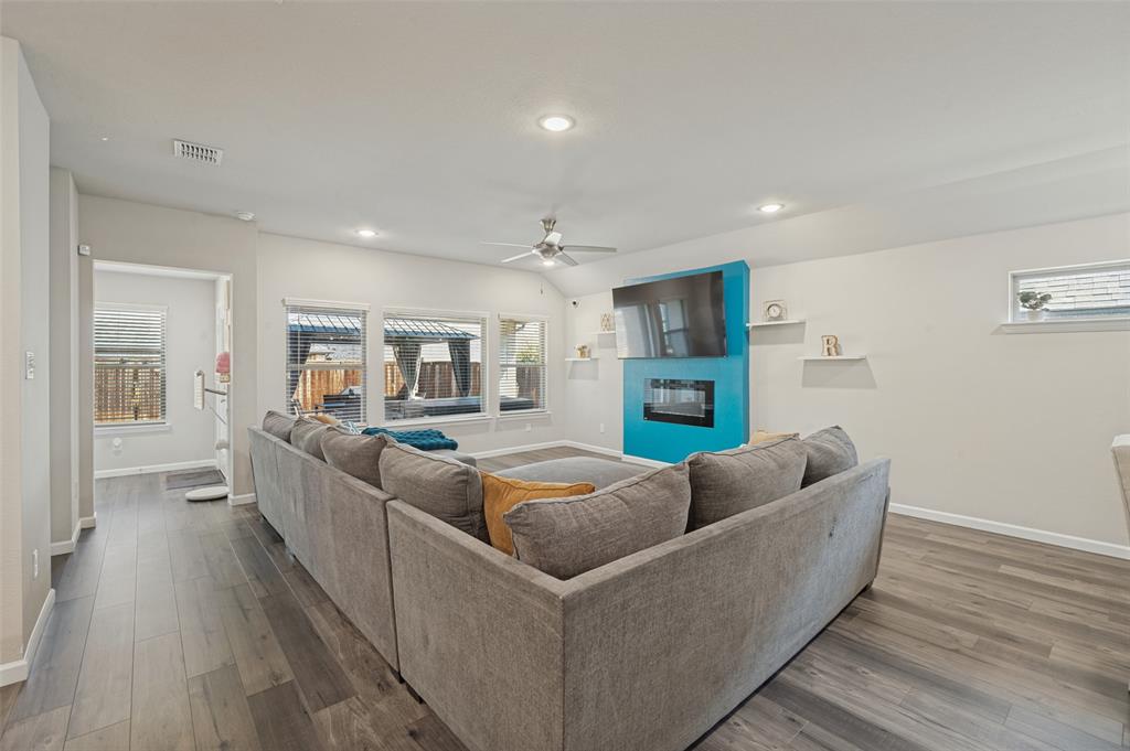 Spacious living area featuring wood-finish flooring, recessed lighting, and a ceiling fan Spacious living area featuring wood-finish flooring, recessed lighting, and a ceiling fan