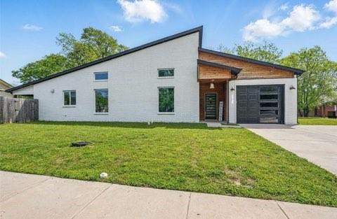 Modern exterior featuring a painted brick facade, asymmetrical roofline, wood-panel accenting, and a garage door with horizontal glass panels