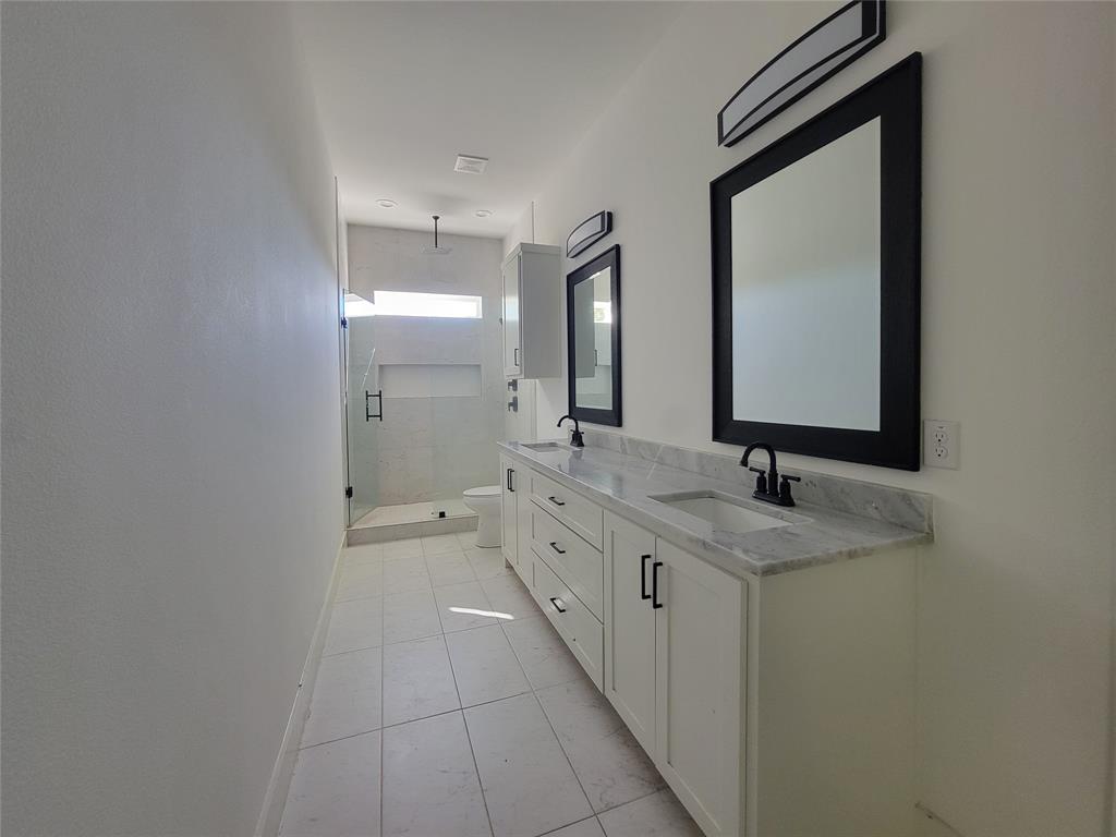 Double vanity featuring white cabinetry, stone-finish countertops, undermount sinks, and matte black fixtures