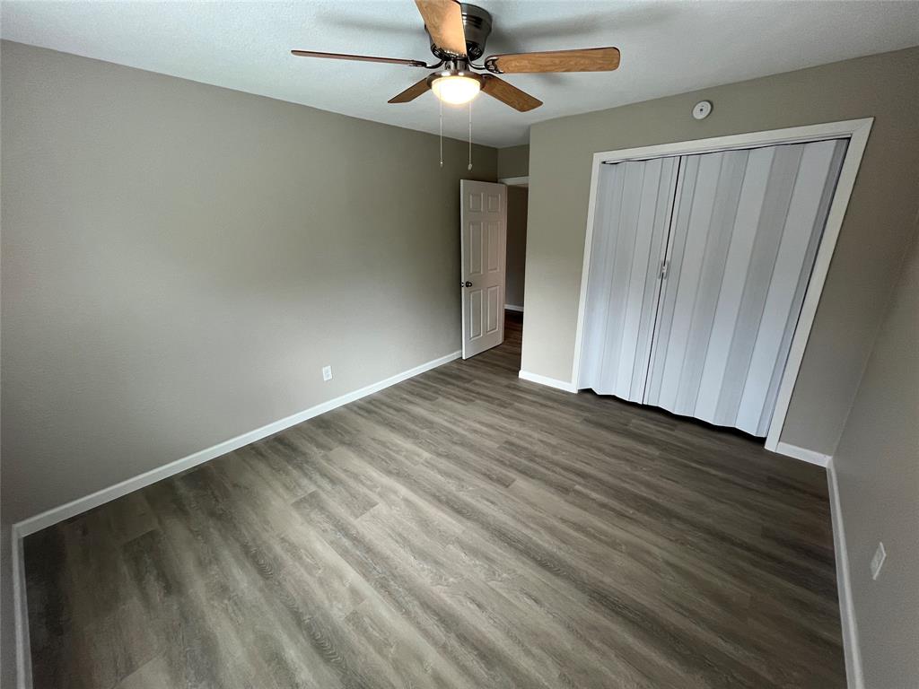 Room featuring wood-finish flooring, a ceiling fan with integrated lighting, and a closet with bifold doors