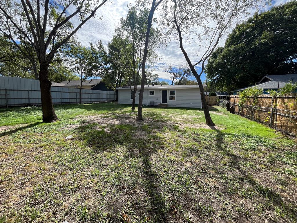 Backyard featuring horizontal siding exterior, perimeter wood and metal fencing, and mature trees