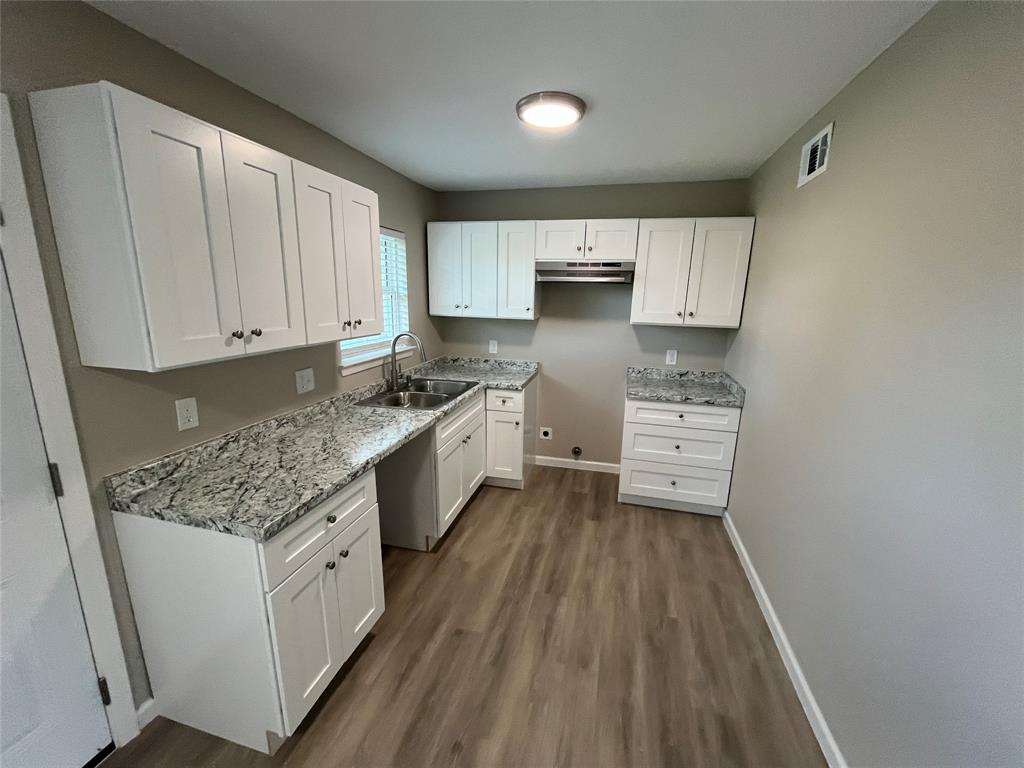 Kitchen featuring white cabinetry, stone-patterned countertops, wood-finish flooring, stainless steel sink with a goose-neck faucet, and a range hood