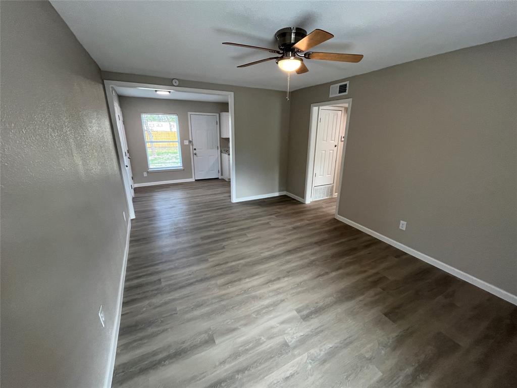 Wood-finish flooring, neutral wall color, ceiling fan with integrated lighting, and multi-panel interior doors