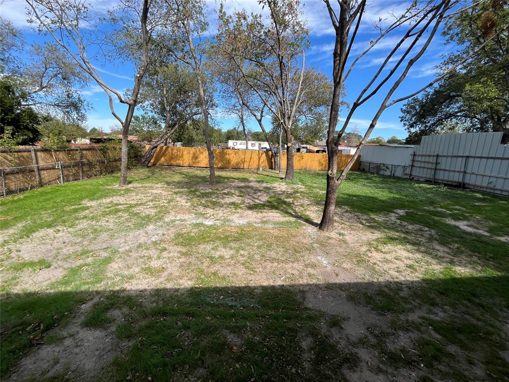Backyard featuring mature trees and wood-style perimeter fencing