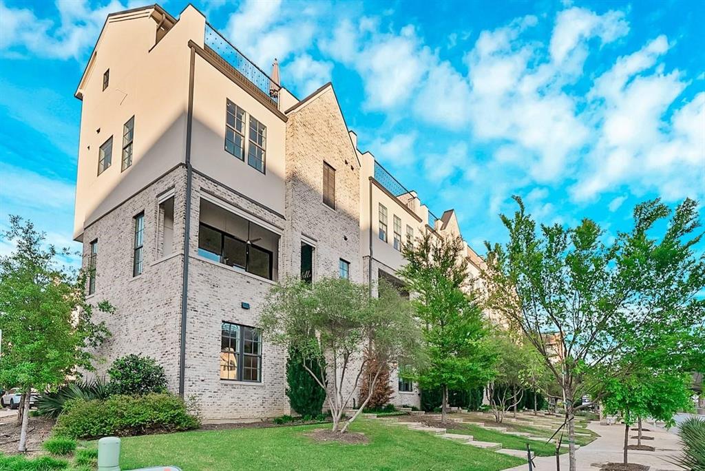 Multi-story exterior with brick and stucco cladding, featuring multiple windows, and an upper-level balcony with a sliding glass door Multi-story exterior with brick and stucco cladding, featuring multiple windows, and an upper-level balcony with a sliding glass door