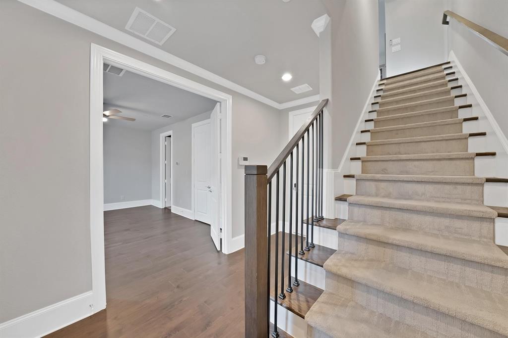 Staircase with carpeted treads, wood risers, and a wrought iron baluster