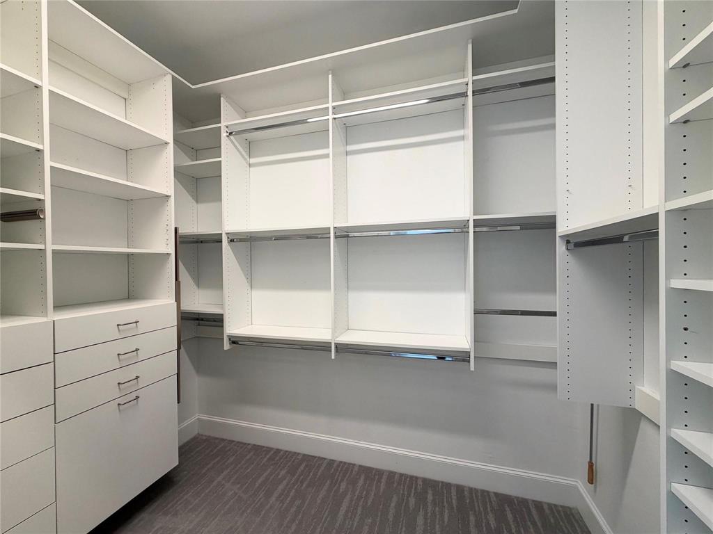 Custom built-in closet system with multiple shelving units, integrated drawers, hanging rods, and a patterned carpet