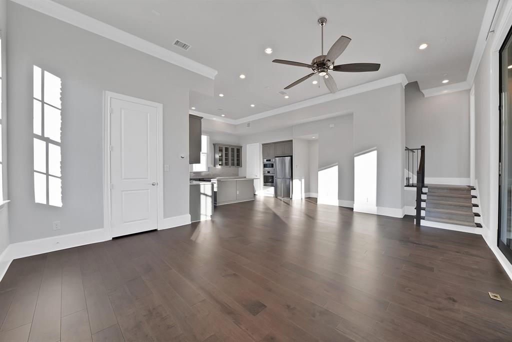 Hardwood-finish flooring, recessed lighting, ceiling fan, crown molding, and a staircase with a black metal railing