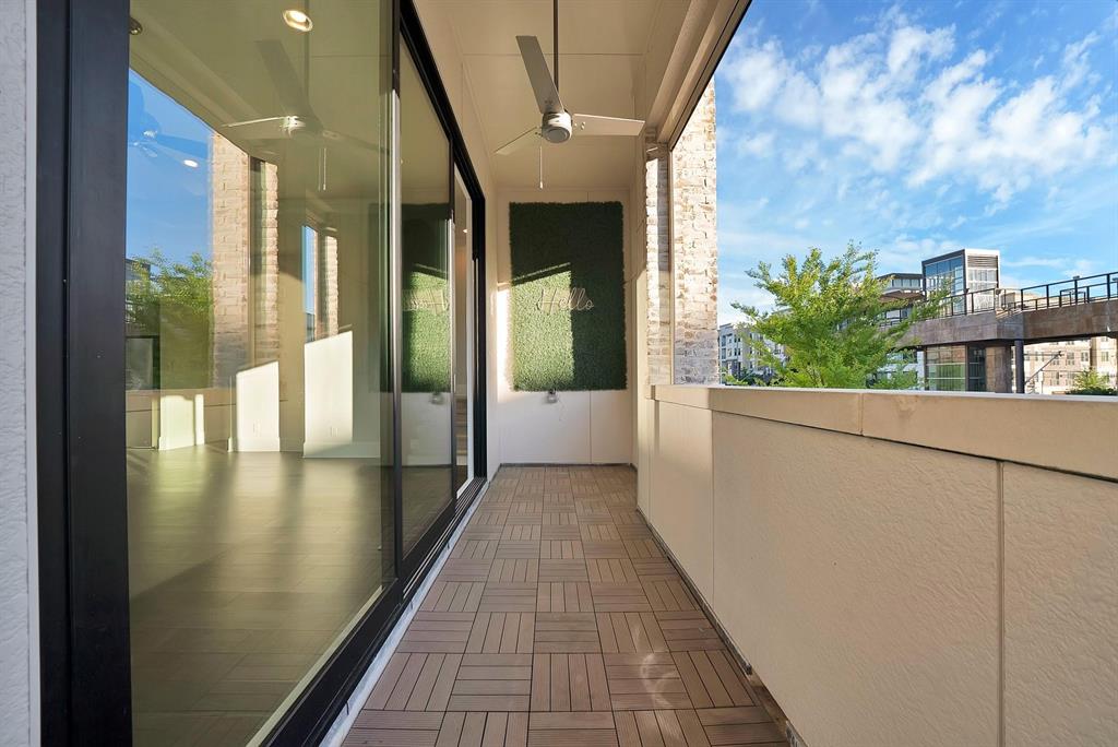 Balcony featuring wood-finish tile flooring, ceiling fan, and sliding glass doors