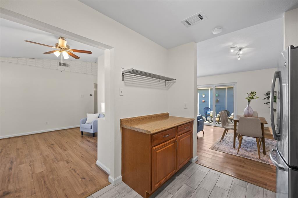 Wood-finish flooring throughout, wood cabinetry with countertop, track lighting, and sliding glass doors