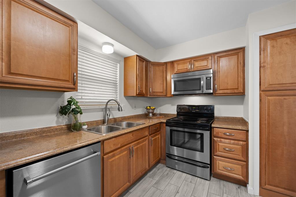 Kitchen featuring wood cabinetry, stainless steel appliances, dual basin sink, and wood-finish flooring