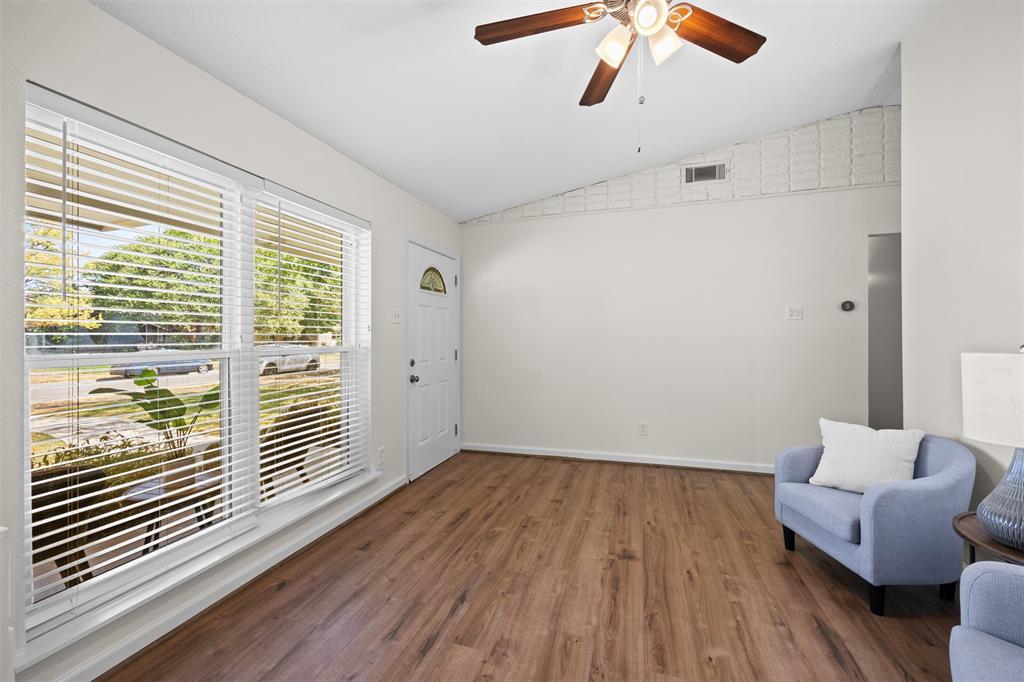 Vaulted ceiling with a ceiling fan, wood-finish flooring, and a window with blinds