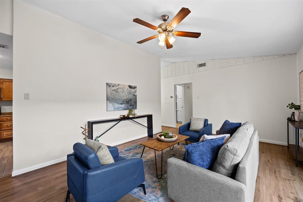 Vaulted ceiling with a ceiling fan, wood-finish flooring, and neutral wall tones