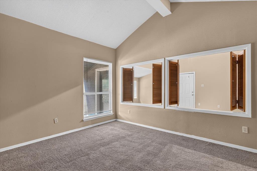 Vaulted ceiling with exposed beam, wall-to-wall carpeting, and a window with exterior visibility