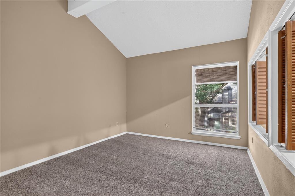 Vaulted ceiling, neutral wall tones, gray carpet, double-hung window, and wooden louvered shutters