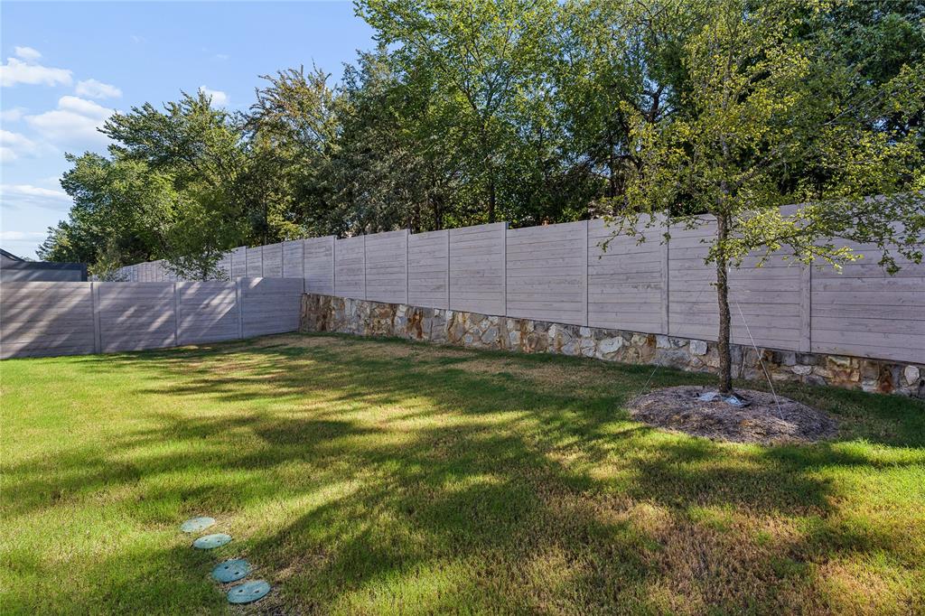 Expansive lawn with a stone retaining wall and a privacy fence